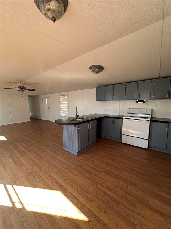 kitchen featuring dark countertops, white electric stove, gray cabinets, and a sink