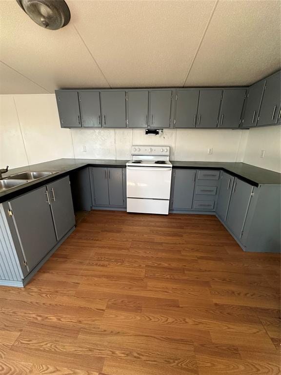 kitchen with dark countertops, gray cabinets, electric range, light wood-style floors, and a textured ceiling