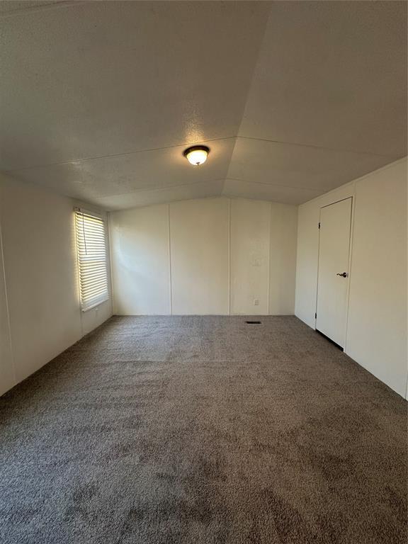 empty room with lofted ceiling and carpet flooring