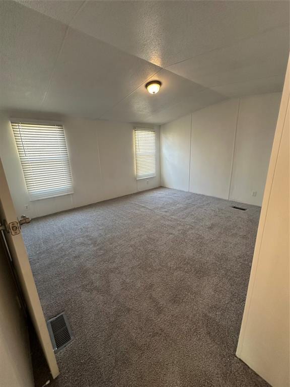 empty room featuring carpet floors, visible vents, and a decorative wall