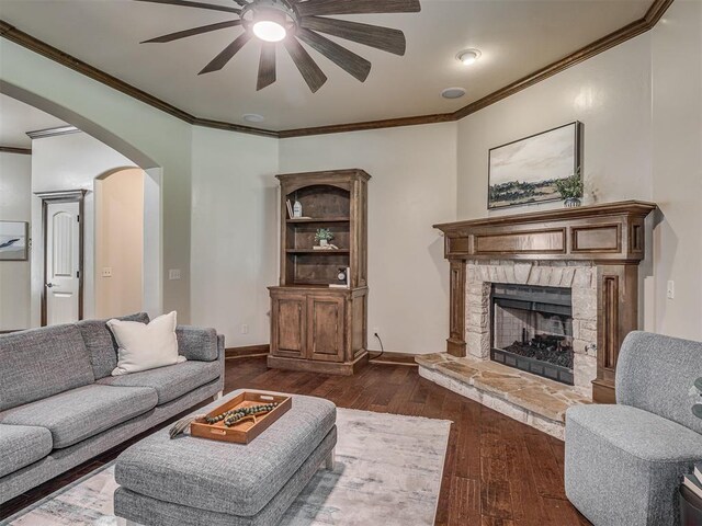 8275 Elk Grv, Blanchard, OK 73010 - living room featuring ceiling fan, arched walkways, dark wood finished floors, crown molding, and a fireplace