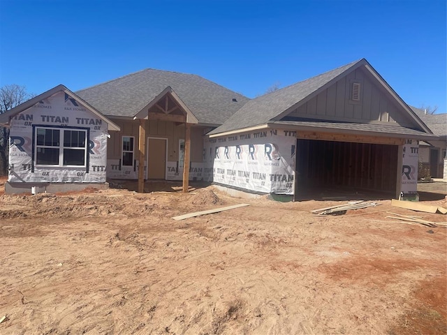 property under construction with a garage, a shingled roof, and board and batten siding