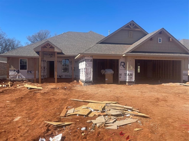 property in mid-construction featuring dirt driveway, roof with shingles, and an attached garage