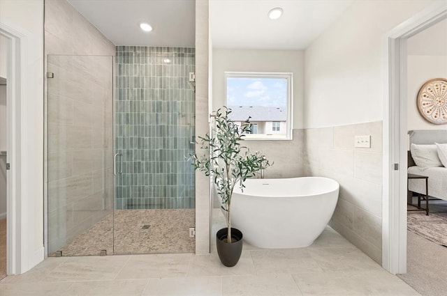 10949 Sandstone Ridge Way, Guthrie, OK 73044 - bathroom with a soaking tub, a shower stall, tile patterned flooring, and tile walls