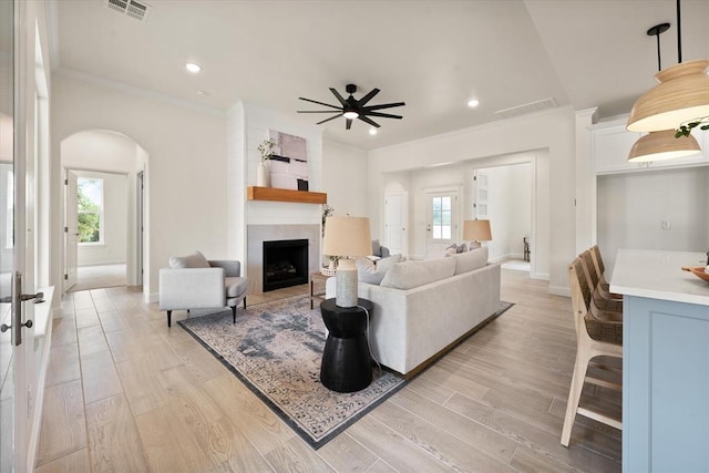 10949 Sandstone Ridge Way, Guthrie, OK 73044 - living area with arched walkways, crown molding, a ceiling fan, a large fireplace, and light wood-style flooring
