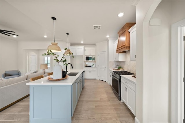 10949 Sandstone Ridge Way, Guthrie, OK 73044 - kitchen with stainless steel appliances, open floor plan, a sink, white cabinetry, and light wood-style floors
