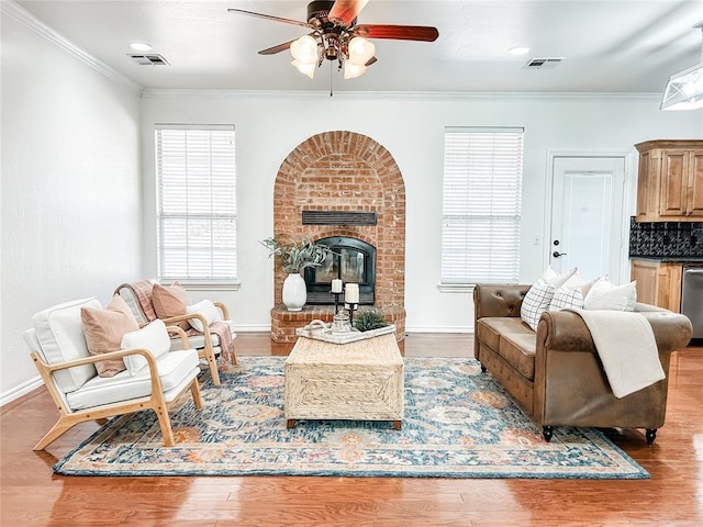 living room with wood finished floors, visible vents, and crown molding