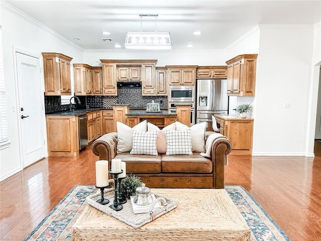 kitchen featuring a center island, crown molding, light wood finished floors, tasteful backsplash, and appliances with stainless steel finishes