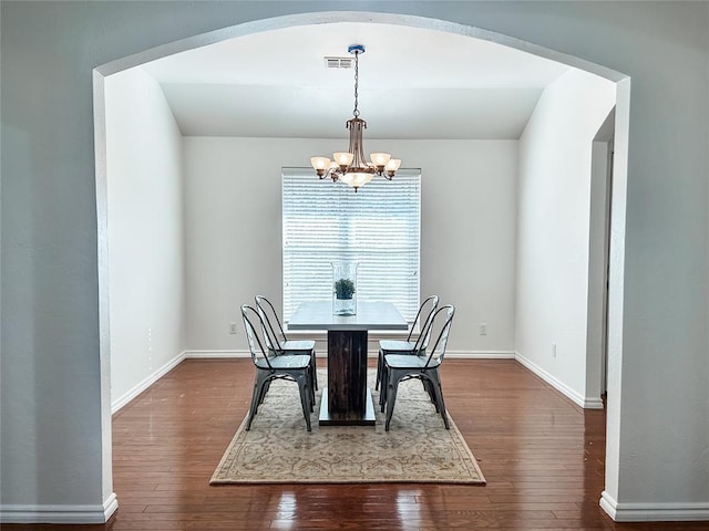 dining room featuring arched walkways, dark wood finished floors, visible vents, an inviting chandelier, and baseboards