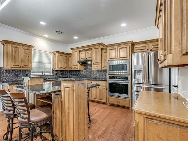 kitchen featuring a center island, a breakfast bar area, visible vents, appliances with stainless steel finishes, and under cabinet range hood