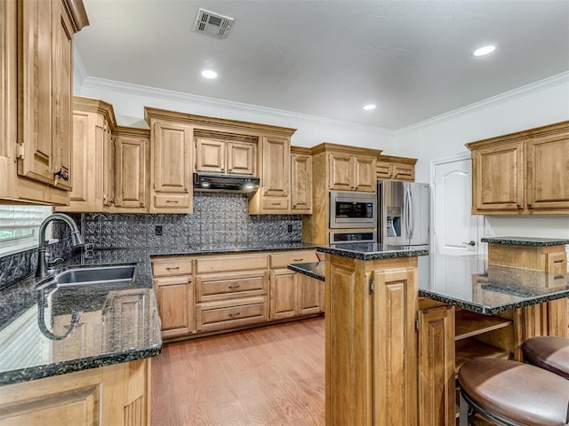 kitchen with under cabinet range hood, stainless steel appliances, a kitchen island, a sink, and visible vents