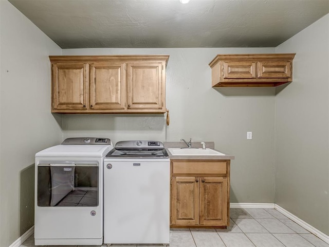 laundry area featuring cabinet space, light tile patterned floors, baseboards, washer and dryer, and a sink