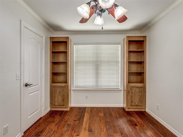 interior space with built in shelves, dark wood finished floors, ornamental molding, ceiling fan, and baseboards