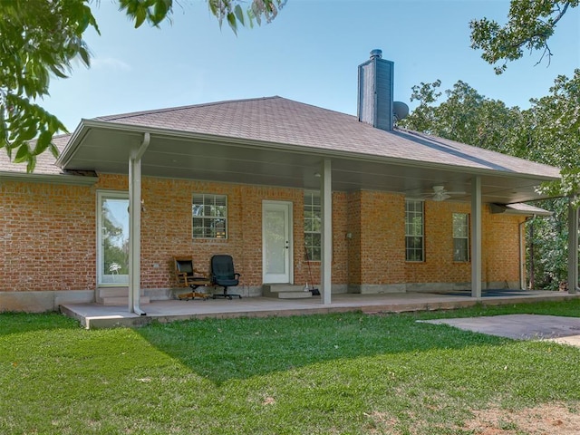 back of house featuring brick siding, a lawn, a chimney, and a ceiling fan