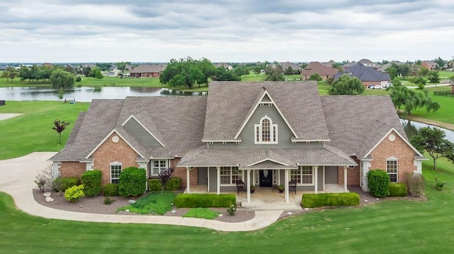 traditional-style home featuring brick siding, a patio area, a front yard, and a water view