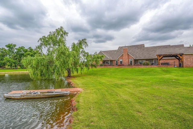 exterior space with a water view, a lawn, and a pergola