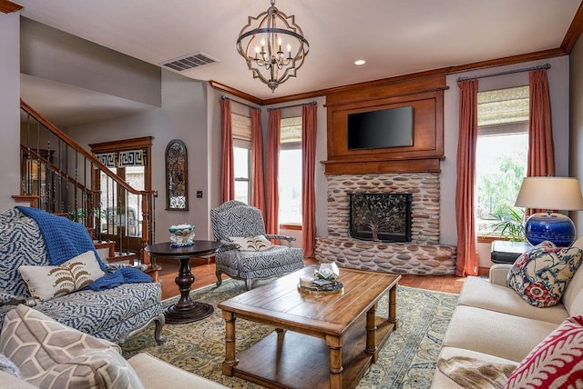 living area with stairway, visible vents, light wood-style flooring, a stone fireplace, and a notable chandelier