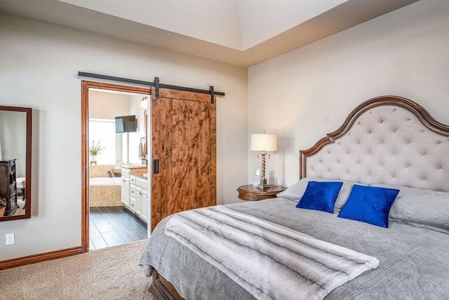 carpeted bedroom with ensuite bath and a barn door