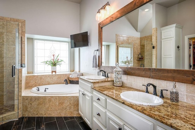 bathroom with a sink, lofted ceiling, a garden tub, and a shower stall