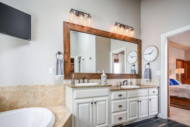 full bath with a sink, connected bathroom, tiled tub, and double vanity