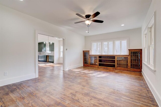 unfurnished living room with wood finished floors, ceiling fan, baseboards, and recessed lighting