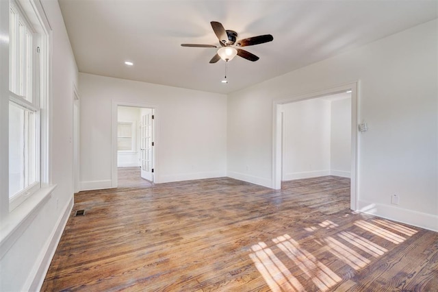 unfurnished room with wood finished floors, ceiling fan, baseboards, and visible vents