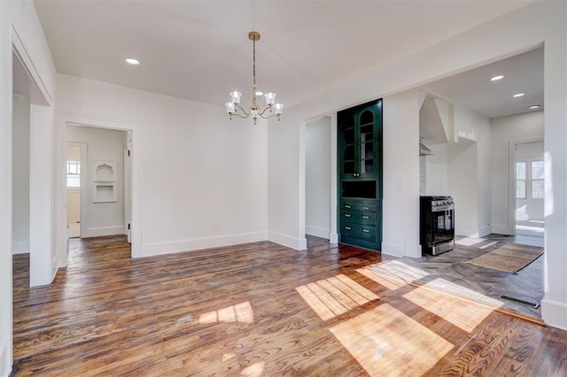 unfurnished dining area with visible vents, baseboards, plenty of natural light, a notable chandelier, and wood finished floors