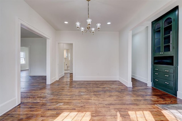 unfurnished dining area with recessed lighting, baseboards, an inviting chandelier, and wood finished floors