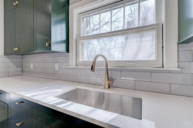 kitchen featuring a sink, light countertops, tasteful backsplash, and green cabinetry