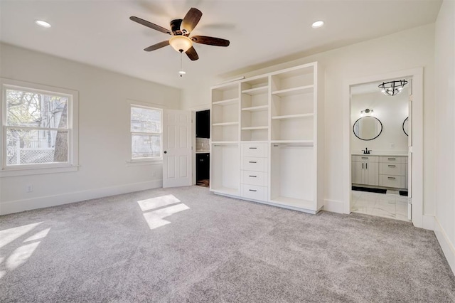 unfurnished bedroom featuring ensuite bath, recessed lighting, light carpet, a sink, and baseboards
