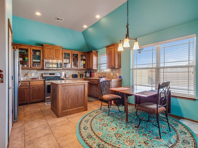 kitchen featuring a center island, decorative light fixtures, stainless steel appliances, light countertops, and glass insert cabinets