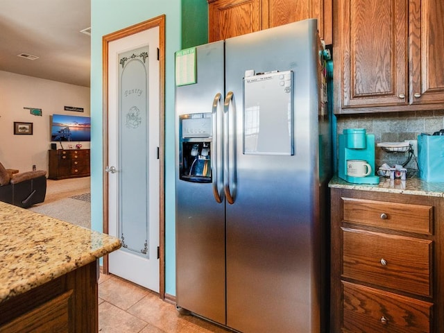 kitchen featuring tasteful backsplash, brown cabinets, visible vents, and stainless steel fridge with ice dispenser