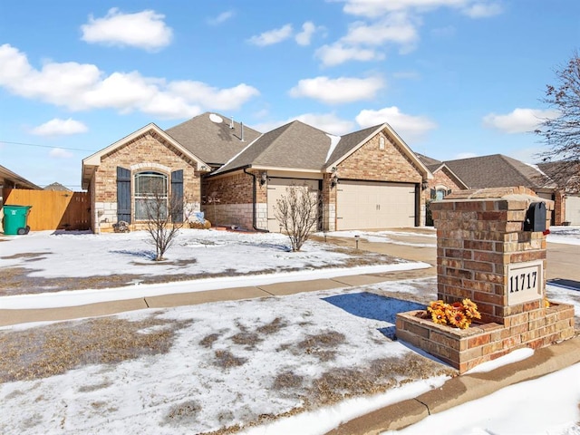 view of front facade with a garage, brick siding, roof with shingles, and fence