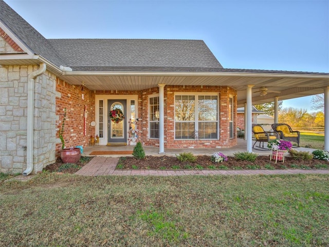 property entrance with stone siding, a porch, a lawn, and a shingled roof