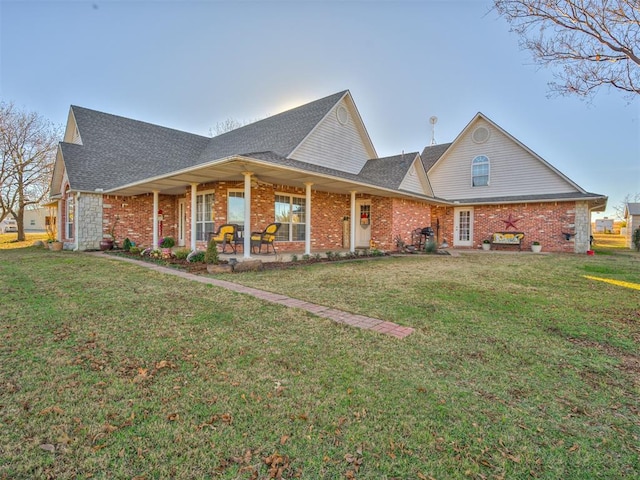 view of front facade featuring roof with shingles, a front lawn, and brick siding