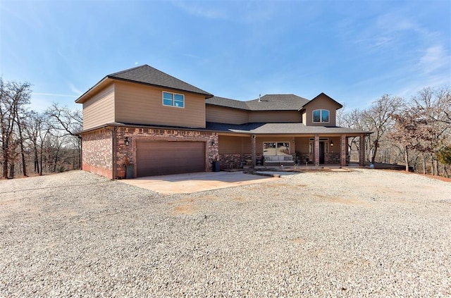 view of front of property with a garage, driveway, brick siding, and covered porch