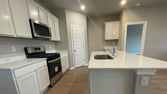 kitchen featuring appliances with stainless steel finishes, light countertops, a center island with sink, and white cabinetry