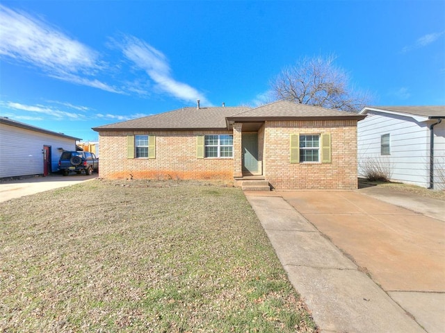 single story home featuring driveway, brick siding, a front lawn, and a shingled roof