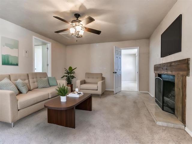 living area featuring a fireplace with raised hearth, baseboards, a ceiling fan, and light colored carpet