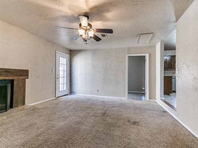 unfurnished living room featuring baseboards, a ceiling fan, a textured wall, a premium fireplace, and carpet