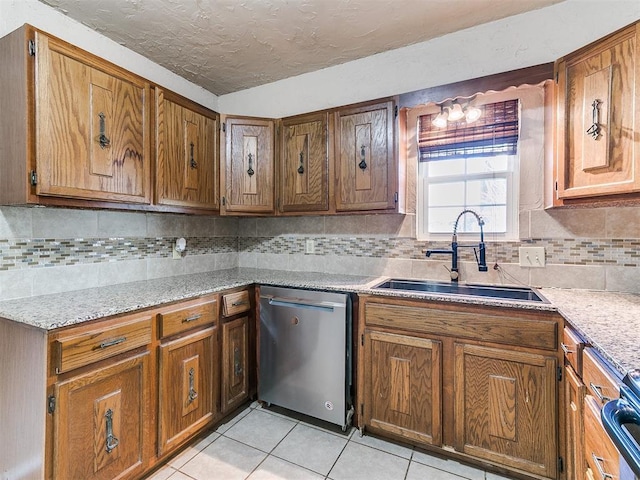 kitchen featuring appliances with stainless steel finishes, a sink, a textured ceiling, backsplash, and light tile patterned flooring