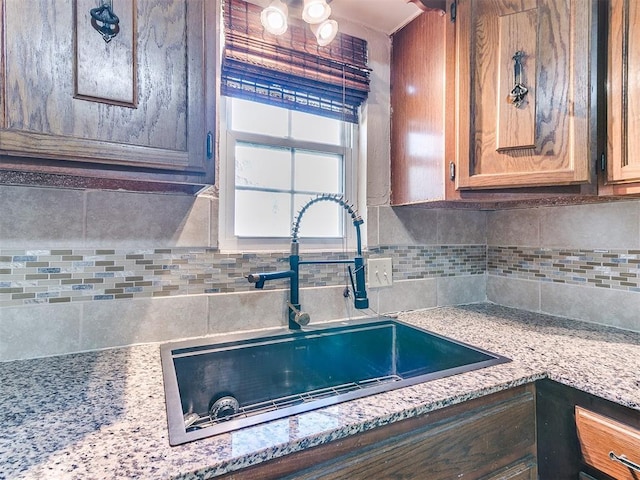 kitchen featuring tasteful backsplash, a sink, and light stone counters