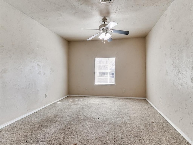 carpeted spare room featuring visible vents, a textured wall, a ceiling fan, and baseboards