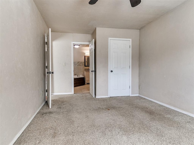 unfurnished bedroom with ensuite bath, carpet flooring, a ceiling fan, and baseboards