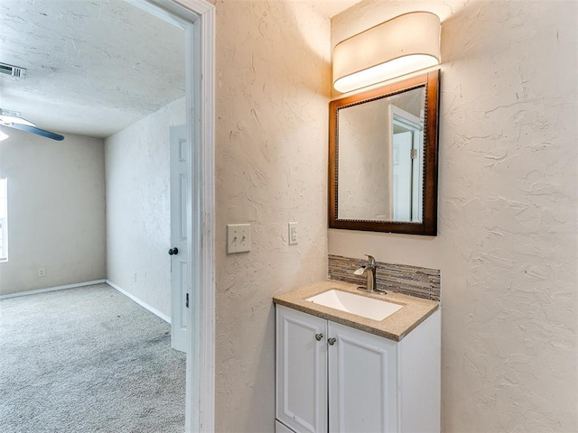 bathroom with a textured wall and vanity