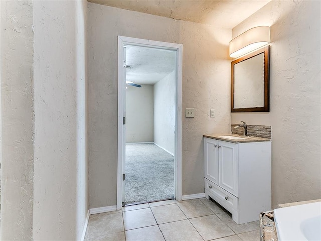 bathroom featuring tile patterned flooring, vanity, baseboards, and a textured wall