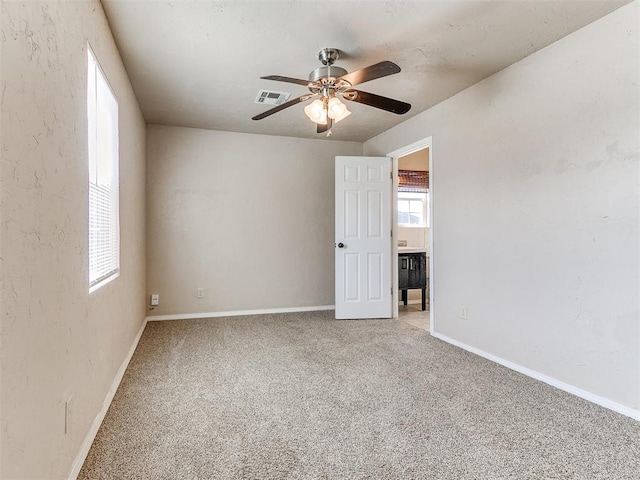 unfurnished room featuring baseboards, visible vents, ceiling fan, and light colored carpet