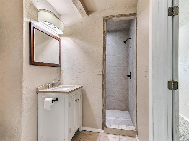 bathroom with a textured wall, tile patterned flooring, a shower stall, and vanity