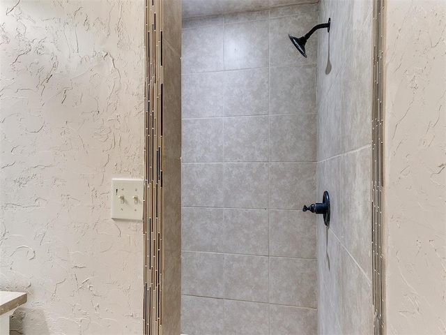 bathroom with tiled shower and a textured wall