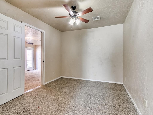 carpeted empty room featuring ceiling fan, baseboards, a textured ceiling, and a textured wall